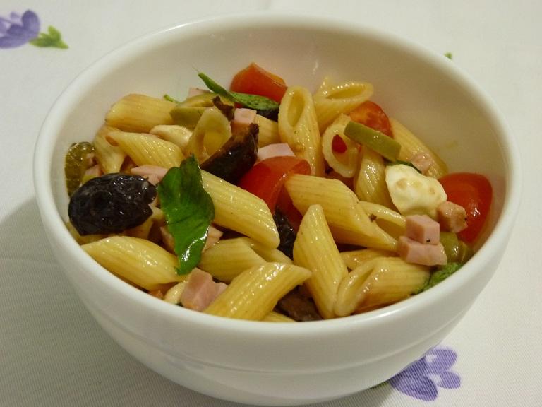 Insalata di pasta fredda con olive, pomodorini, prosciutto e mozzarelline